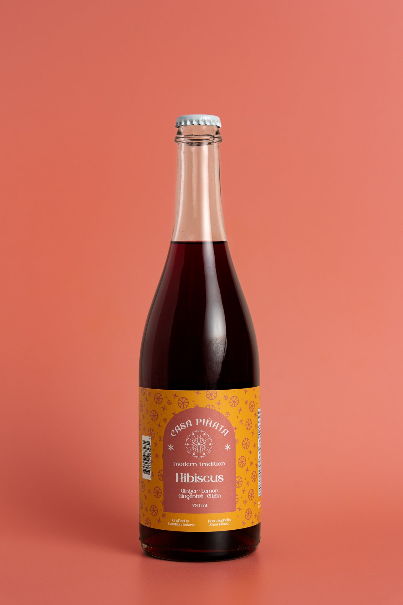 750 ml clear champagne bottle of Casa Piñata Hibiscus Spritzer against a red background.